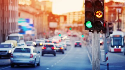 Autos fahren am späten Abend durch eine Stadtstraße, beleuchtet von Straßenlaternen und Scheinwerfern.